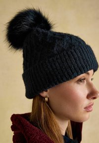 Knitted dark blue beanie with a faux fur pom-pom on top. Features a ribbed texture and a close-fitting design.