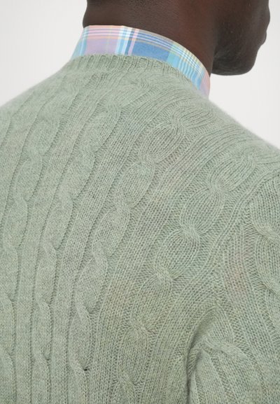 Camisola verde-claro de malha com padrão texturizado, com gola de camisa aos quadrados multicolorida em tons de rosa, azul e verde.