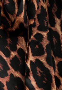 Pälstryck i leopardmönster med svart bakgrund och bruna och tan-fläckar. Texturen verkar slät och mjuk vid beröring.