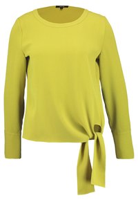 Pitkähihainen paita kirkkaasta keltaisesta kankaasta, jossa on pyöreä pääntie ja sivusolmu helmassa. Sujuva rakenne, yksinkertainen muotoilu ja tiukka istuvuus.