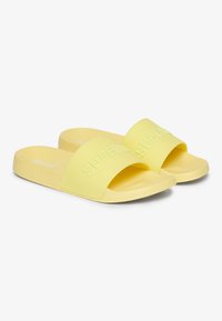 Yellow rubber slides with wide straps. The strap features embossed "SUPERDRY" text. Smooth, matte finish and contoured footbed for comfort.