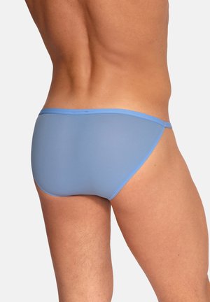 Męski tors i górna część nóg widziane od tyłu, ubrane w jasnoniebieskie majtki typu slipy na jednolitym tle.