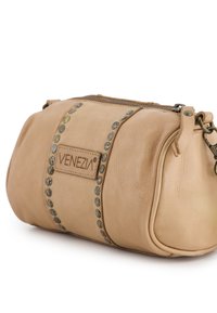 Tan leather bag with rounded shape, featuring decorative metal studs along the center and a zip closure at the top. Branding visible.