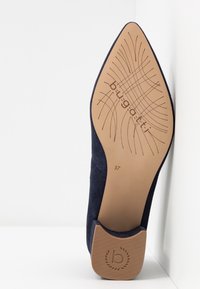 Semelle d'une chaussure bleu marine à bout pointu avec une semelle beige texturée présentant le logo Bugatti, la taille 37 et un petit talon bloc.