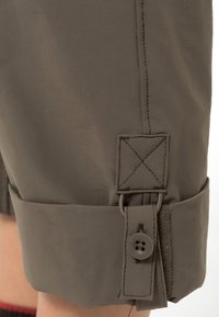 Pantalones cortos caqui con puños enrollados, cierre de botón y costuras en contraste. Tejido suave con un brillo sutil y detalles de diseño funcionales.