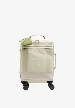 Beżowa walizka z przednimi kieszeniami z siateczki, górnymi i bocznymi uchwytami, czterema czarnymi kółkami oraz małą zieloną saszetką na suwak przymocowaną do górnej rączki.
