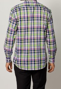 Rutig skjorta med gröna, lila och marinblå färger; långa ärmar; knäppning vid ärmsluten; böjd nederkant; rutmönster och mjuk tygkvalitet.