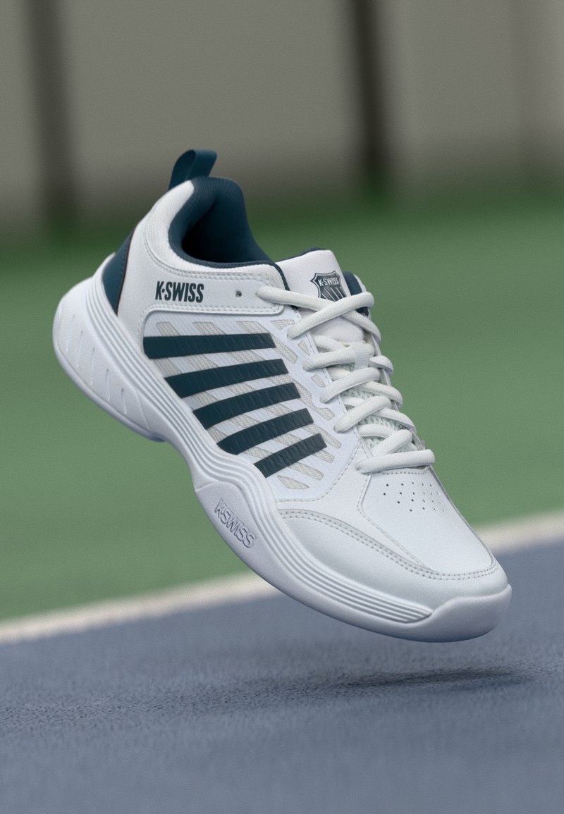 Bijela atletska cipela s zelenim detaljima, vezanje na vezice, perforirani gornji dio i istaknuto K-Swiss brendiranje sa strane i na jeziku.