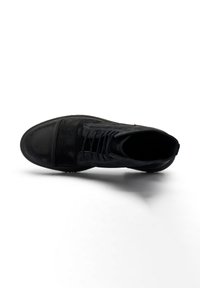 Stivale alla caviglia in suede nero con punta tondeggiante, dotato di lacci, una tomaia testurizzata e una suola piatta in gomma.