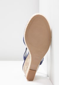 Sandaľ s klinovým podpätkom, modrým textilným zvrškom, korkovou strednou podrážkou a béžovou gumovou podrážkou označenou "New Look", veľkosť 4/37, položená na podrážke hore.