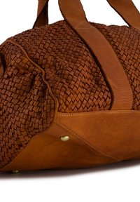 Gevlochten tan leren reistas met gladde leren accenten, voorzien van stevige handvatten, een ronde vorm en decoratieve stikdetails.