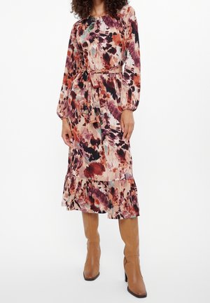 Vestido midi floral en tela suave, con mangas largas, cintura con cinturón y dobladillo con volante. Los colores incluyen tonos de rosa, rojo y negro.