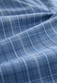 Blue fabric with a tight plaid pattern featuring light blue and white vertical and horizontal lines creating a textured grid design.
