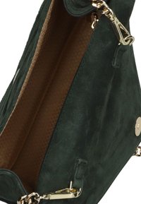 Groene suède handbag met een gouden kettingband, voorzien van een hexagonaal textuur bruin interieur en een met rits afsluitbaar vak.