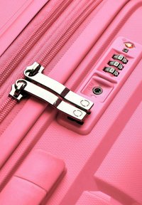 Rosa Gepäckstücke mit strukturiertem Oberflächenmaterial, ausgestattet mit einem silbernen Reißverschluss und einem Kombinationsschloss. Das Design weist eine runde Form und verstärkte Ecken auf.