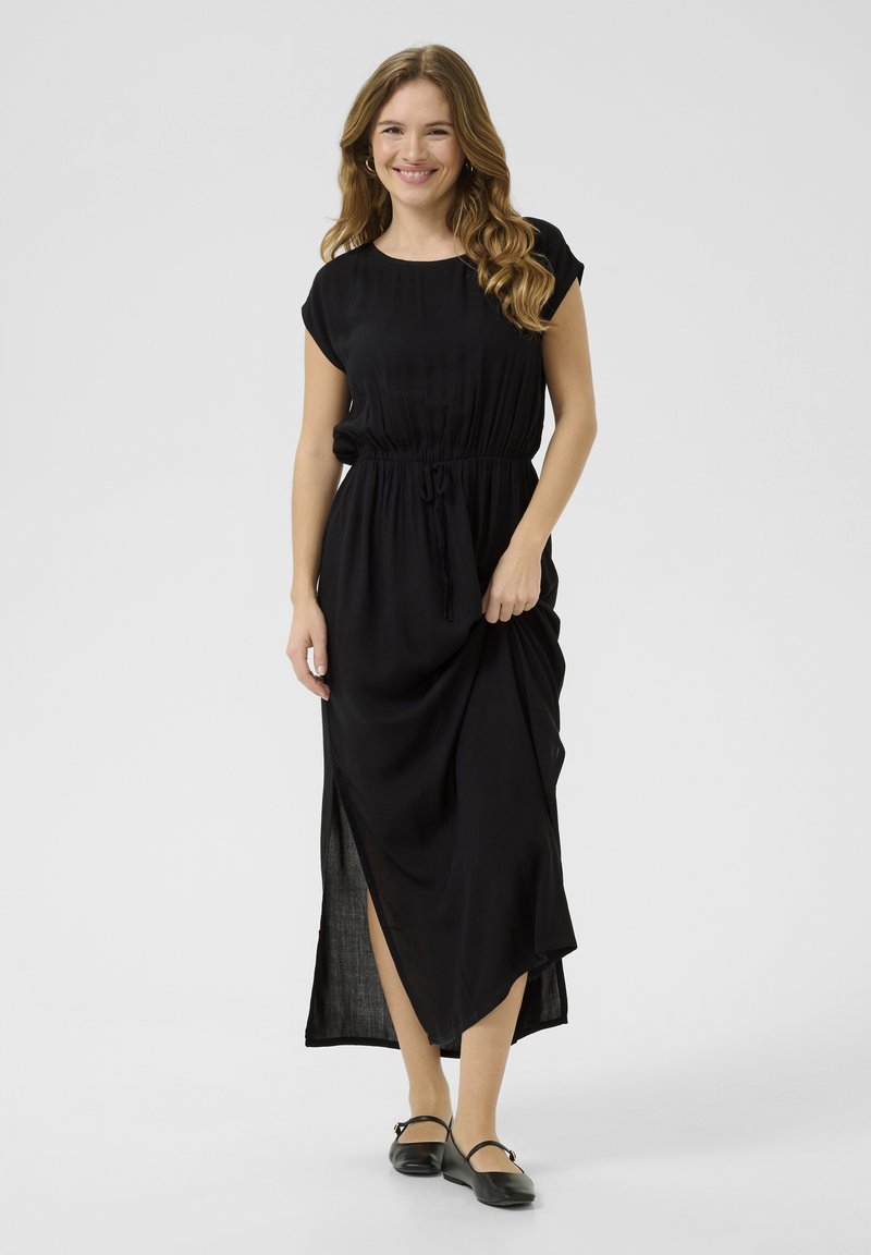 Black maxi dress with short sleeves, drawstring waist, and side slit. Lightweight fabric drapes softly, creating a relaxed silhouette.