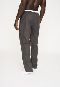 Gray pants with a textured fabric, featuring an elastic white waistband, a back pocket, and a relaxed, straight-leg design.