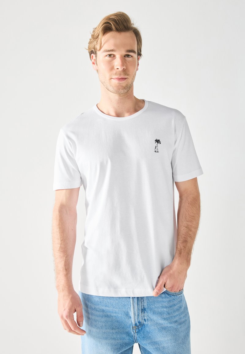 Witte T-shirt met korte mouwen, gemaakt van katoen, met een ronde halslijn en een kleine zwarte palmboom grafiek op de linker borst.