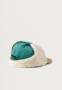 Teal värvi kordsatiinist ülemise osaga müts, kreemjas fleecemüüri ja pruunis lame äärega. Omab tõmblukuga taskut ja nööri mõõtmete reguleerimiseks.