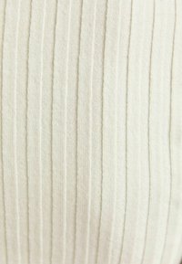 Krämfärgad tyg med vertikal ribbad textur och subtilt vävdiagram.