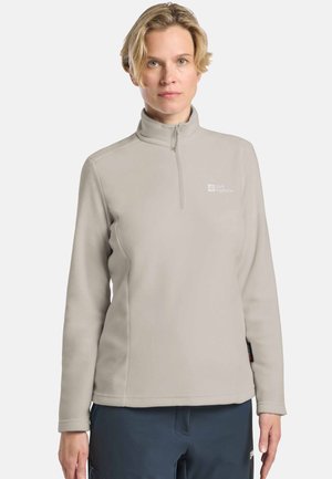 Lichtgrijze fleece pullover met een ritssluiting in de nek, lange mouwen en een logo op de borst. Materiaal lijkt zacht met een gladde textuur.
