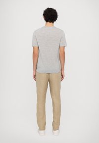 Gray short-sleeve shirt with a rounded neckline, paired with light beige linen pants. The outfit features a relaxed fit and soft texture.