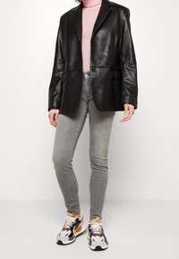 Black leather blazer, pink turtleneck, gray skinny jeans, and multicolored sneakers. Blazer has two buttons and side pockets.