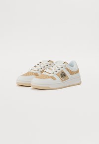 Sko med en overdel i hvitt skinn og beige mesh, strukturerte detaljer, gullmerke og en tykk hvit såle med en lys beige relieff.