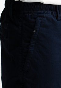 Navyblauwe shorts van zachte stof, met een elastische tailleband, zijzakken en een klein logo label aan de voorkant.