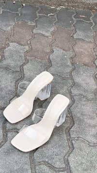 Bež sandale na visoku petu imaju prozirne trake i prozirnu blok petu. Upravni dizajn prsta poboljšava moderne estetske elemente.
