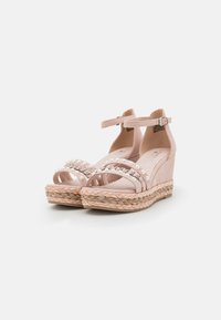 Las sandalias de cuña rosas cuentan con un diseño de upper similar al ante, múltiples correas adornadas con perlas falsas y una plataforma envuelta en yute con un acabado texturizado.