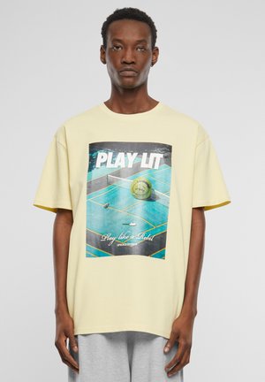 Gul bomull t-skjorte med grafisk trykk av en tennisbane og ball, med teksten "PLAY LIT" og "Play like a Rebel" i kontrasterende farger.