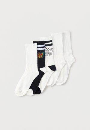 Fünf Paar Sportsocken, überwiegend weiß, davon zwei mit Schmetterlingsmotiven – eines bunt auf Schwarz, eines mit schwarzer Umrandung auf Weiß mit Streifen.