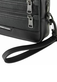 Borsa a mano in pelle nera con corpo texturizzato, multiple tasche con zip e tracolla rimovibile. Presenta dettagli in hardware argentato e il logo.