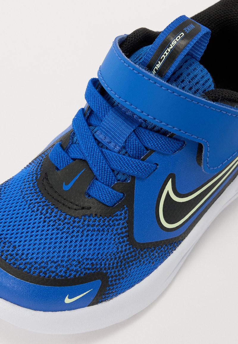 Blauwe sportschoen met mesh bovenwerk, rubberen zool, zwarte accenten en verstelbare riem. Heeft een gestructureerd oppervlak en merkelementen.