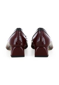 Scarpe in pelle verniciata bordeaux con tacco basso a blocco, dettagli neri sulla parte superiore e una texture liscia e lucida. La vista posteriore mostra un design arrotondato.