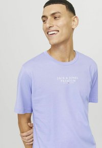 Šviesiai purpurinė medvilninė marškinėliai su apvali iškirpte ir trumpomis rankovėmis, ant krūtinės baltu spalva esantis "Jack & Jones Premium" logotipas.