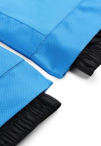 Tessuto blu, textured con una leggera lucentezza, caratterizzato da una fodera nera liscia e arricciature elastiche ai bordi per una vestibilità regolabile.