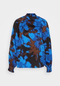 Blouse à manches longues avec col et poignets smockés hauts, présentant un motif abstrait bleu, marron et noir sur un tissu léger.