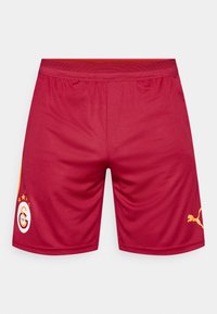 Rote Sportshorts mit elastischem Bund, versehen mit einem gelben Logo und Akzenten sowie einer glatten Stoffstruktur. Keine sichtbaren Muster.