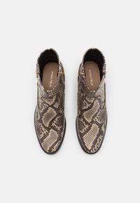 Bottines à motif peau de serpent en nuances de marron et beige, dotées de fermetures éclair latérales et d'une semelle noire basse texturée.