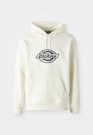 Krém színű kapucnis pulóver puha anyagból, elülső zsebbel. Fekete logóval ellátott kör alakú mintával rendelkezik. Bordás mandzsetták és alsó szegély.