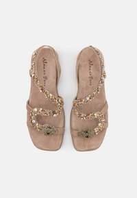 Béžové semišové sandály s dekorativním korálkovým designem hada, s klenotem na špičce. Texturovaná stélka a otevřený styl.