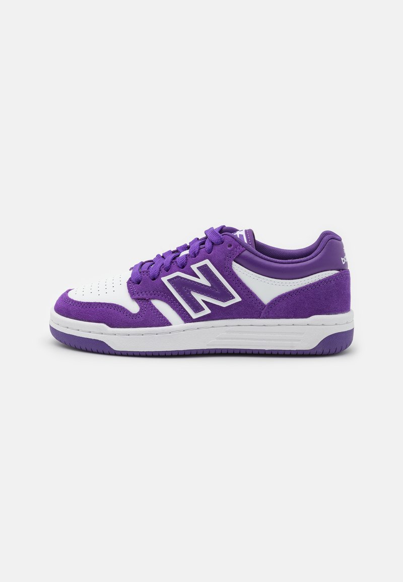 Sneaker viola con una punta in pelle bianca, accenti in suede viola e un logo bianco audace. La suola è texturizzata per garantire aderenza.