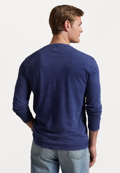 Μπλουζάκι από βαμβάκι σε ναυτικό μπλε χρώμα με μακριά μανίκια, στρογγυλή λαιμόκοψη και αναδιπλωμένα μανίκια. Διαθέτει λεία υφή και χαλαρή εφαρμογή.