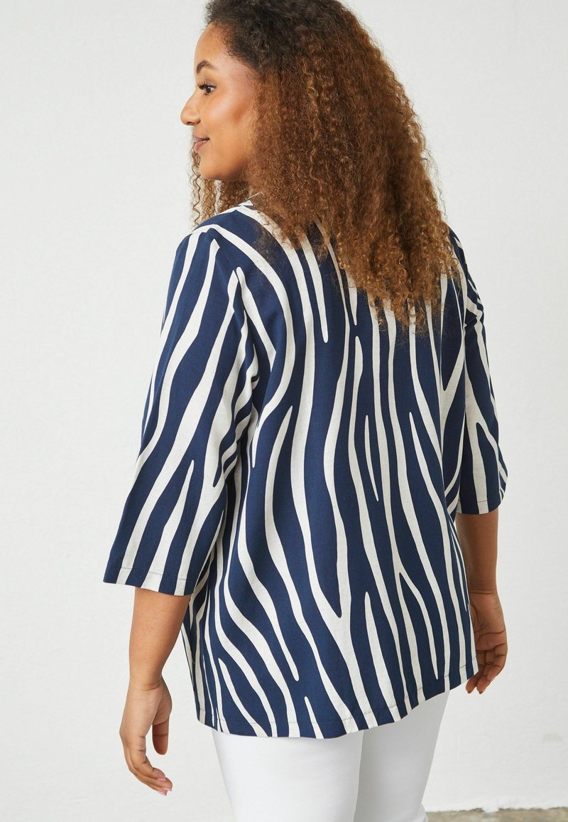 Blusa a righe navy e bianche con maniche 3/4, caratterizzata da una vestibilità ampia e fondo curvo. Tessuto testurizzato con una sensazione morbida.