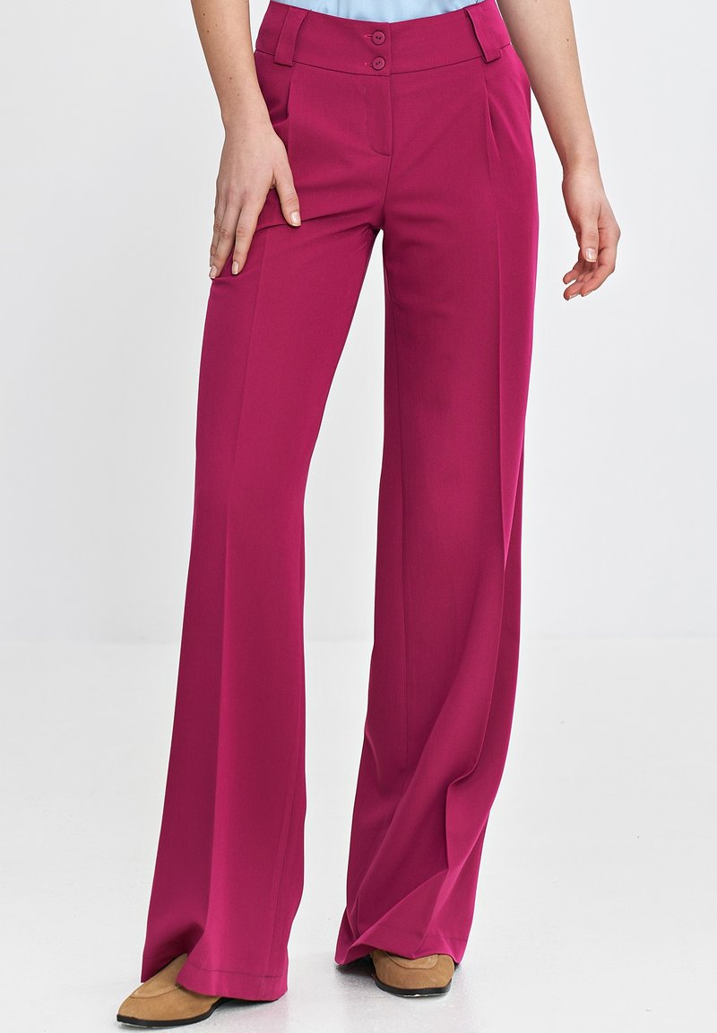 Fuksjowe spodnie o szerokich nogawkach z gładką teksturą, z dwoma przednimi guzikami i plisami z przodu, w połączeniu z jasnoniebieską bluzką i brązowymi butami.