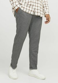 Grå tapered byxor i en texturerad tyg, med sidfickor, i kombination med vita sneakers och en rutig skjorta.