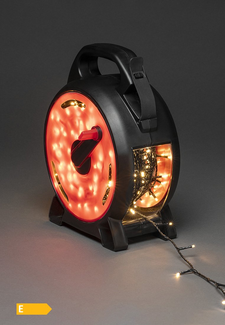 Carrete circular negro y rojo con una manija, que sostiene luces de cuerda. Superficie texturizada con un bobinado visible de luces de hadas saliendo por un costado.