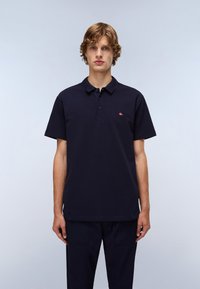 Marine polo skjorte med krage, med fire knapper og et lite brodert flagglogo på brystet. Korte ermer og en glatt tekstur.